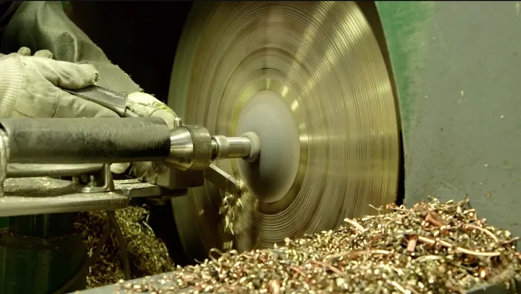 Cymbal being turned on a lathe to cut tonal grooves
